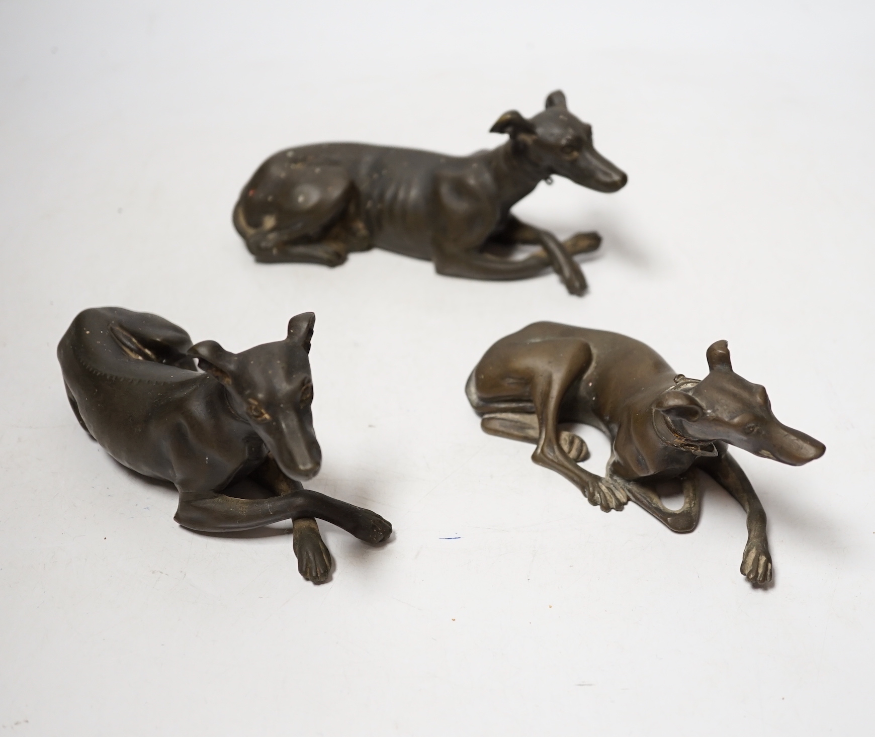 Three late 19th century bronze models of recumbent greyhounds, 17cm